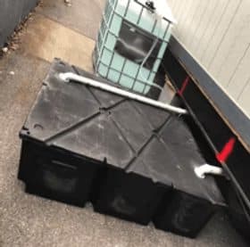 Holding tank installed beside a building with plumbing connected