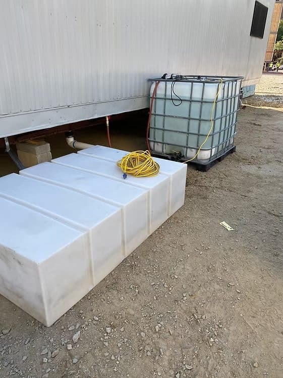 Holding tanks and a fresh water supply plumbed under a job-site office trailer