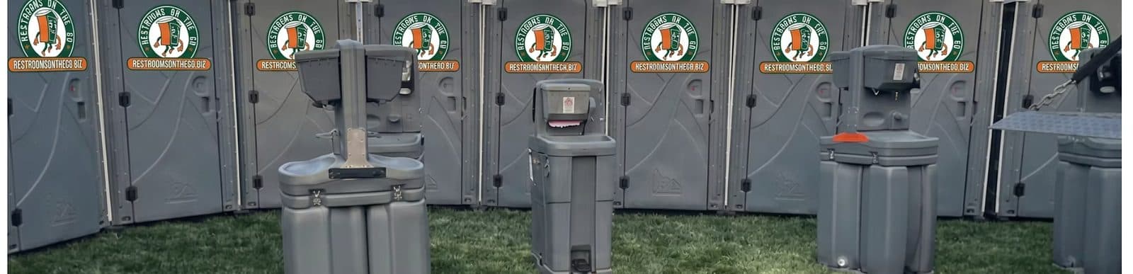 A row of portable restrooms with handwashing stations set up for a crowd