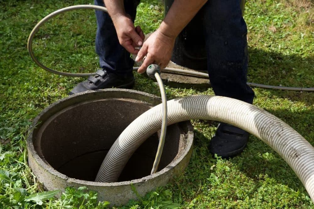 Technician pumping a septic tank through the access port